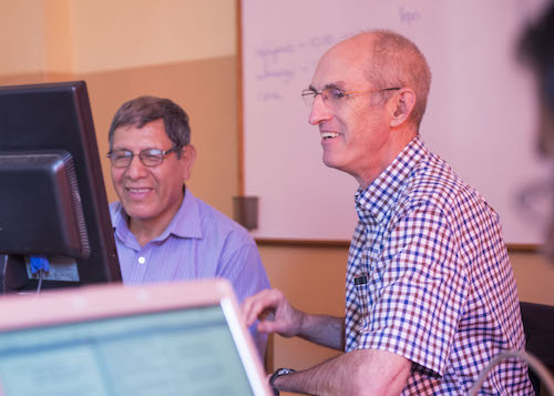 Mark and a translator work together at their computers.